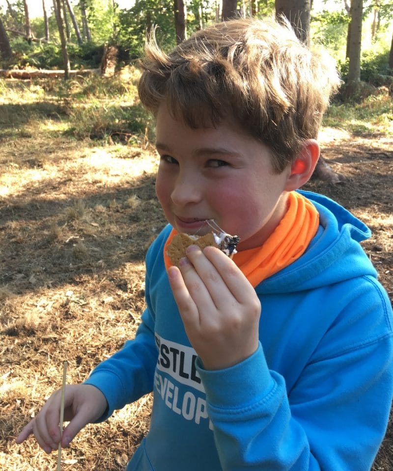 Pinewood Prep School Year 6 boy enjoys camp fire smores on the bushcraft adventure trip to Blenheim Woods